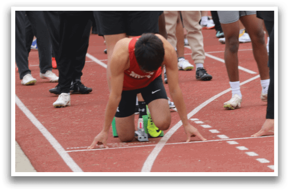 A group of people are lined up on a track. Description generated by AI