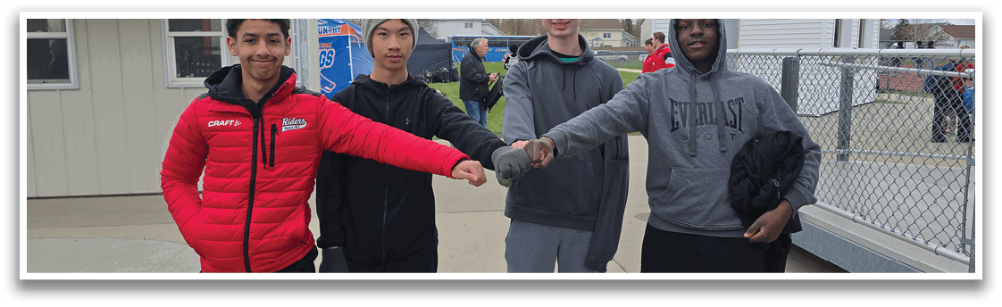 Four young men standing together, shaking hands. Description generated by AI