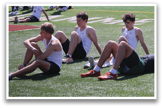 A group of men are sitting on the grass. Description generated by AI