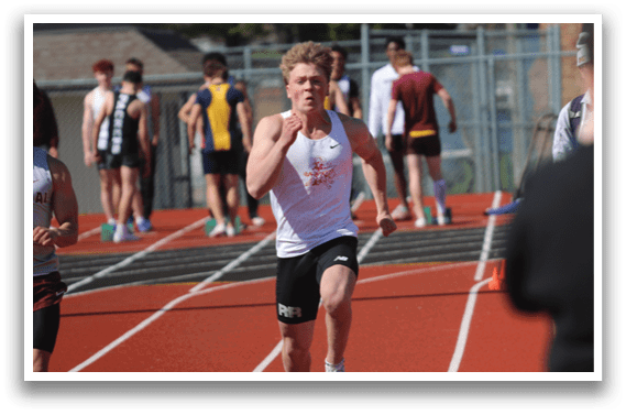 A man running on a track with a white shirt and black shorts. Description generated by AI