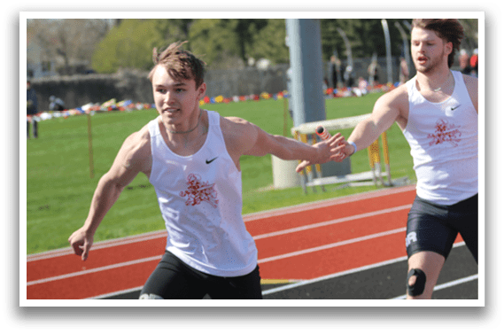 A man running on a track with a white shirt and black shorts. Description generated by AI