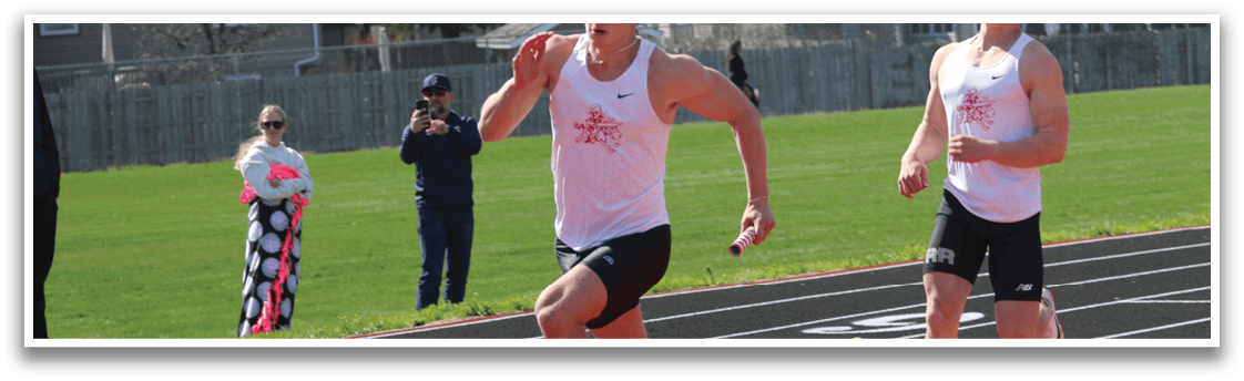 A man running on a track with a red shirt. Description generated by AI