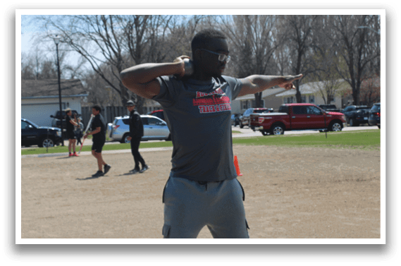 A man is standing on a field with his arms outstretched. Description generated by AI