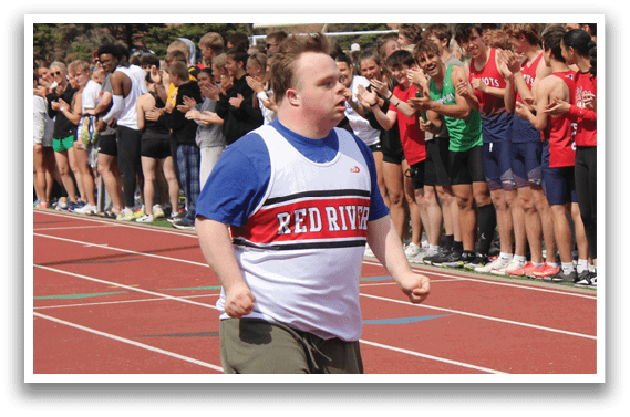 A man running on a track with a crowd of people watching. Description generated by AI
