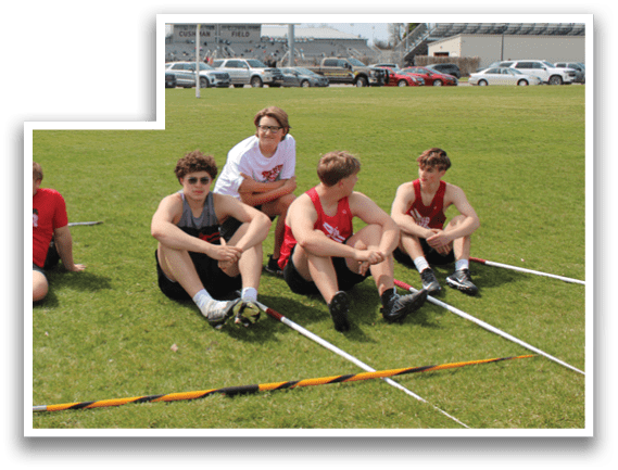 A group of young men sitting on the grass. Description generated by AI