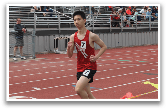 A man running on a track with a red shirt and black shorts. Description generated by AI