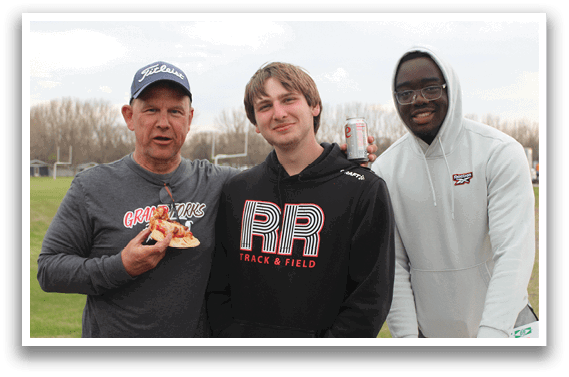Three men standing together, one of them holding a can of soda. Description generated by AI