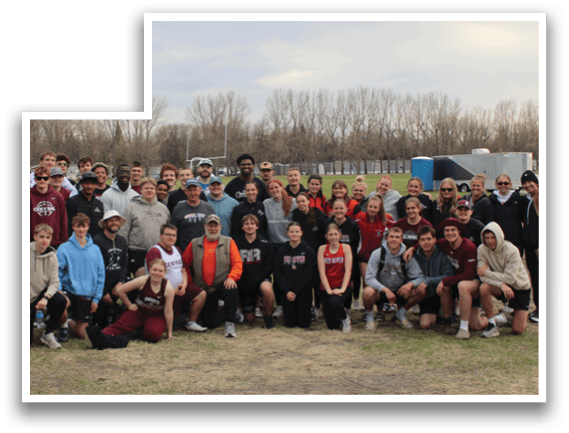 A group of people posing for a picture on a field. Description generated by AI