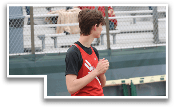 A boy wearing a red and black shirt stands on a track. Description generated by AI