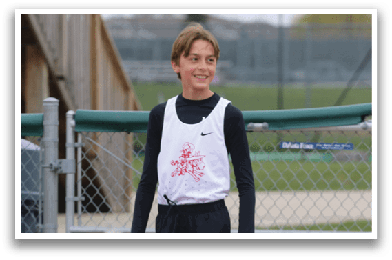 A boy wearing a white shirt and black shorts is standing on a track. Description generated by AI