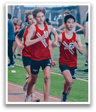 A boy running on a track with a red shirt and black shorts. Description generated by AI