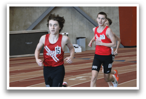A boy running on a track with a red shirt and black shorts. Description generated by AI