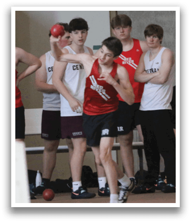 A group of men wearing red shirts and black shorts are standing in a line. Description generated by AI