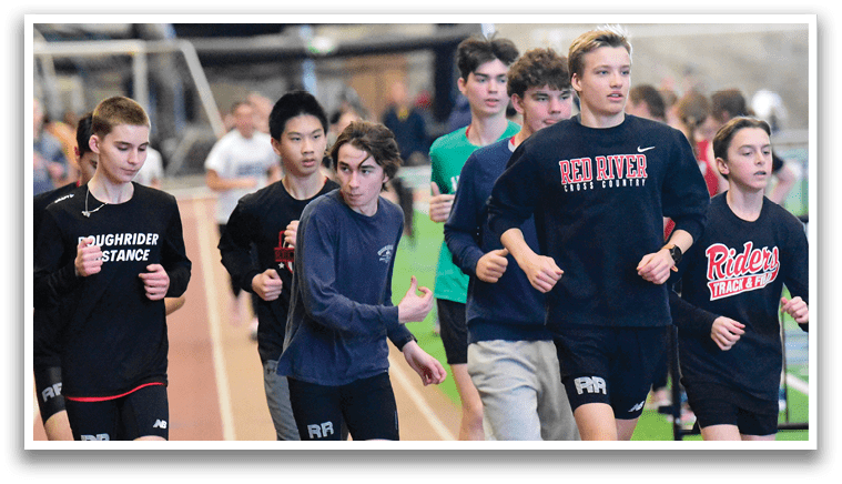 A group of young men running on a track. Description generated by AI