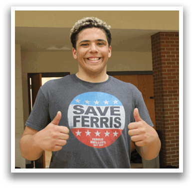 A man wearing a gray shirt with a red, white, and blue design giving a thumbs up. Description generated by AI