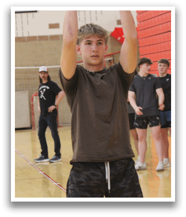 A man holding a black ball in a gym. Description generated by AI