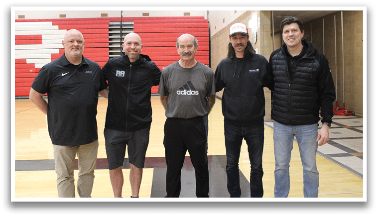 A group of men standing in a gym. Description generated by AI
