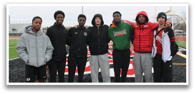 A group of young men posing for a picture on a football field. Description generated by AI