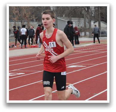 A runner in a red shirt and black shorts is running on a track. Description generated by AI