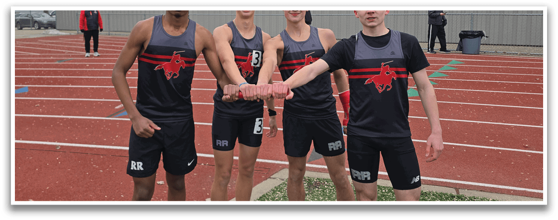 Four young men standing on a track field. Description generated by AI