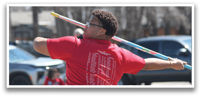 A man in a red shirt is holding a pole and swinging it. Description generated by AI