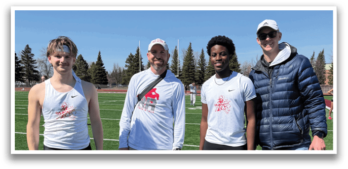 Four people standing on a field. Description generated by AI