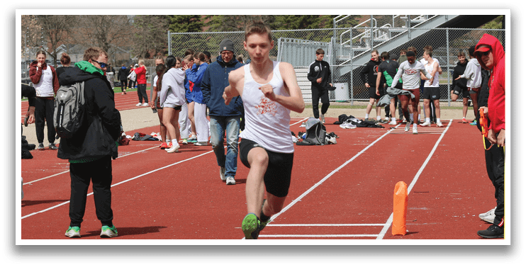 A boy running on a track with a cone in front of him. Description generated by AI