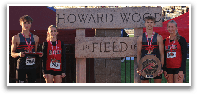 A group of people standing in front of a sign that says Howard Wood. Description generated by AI
