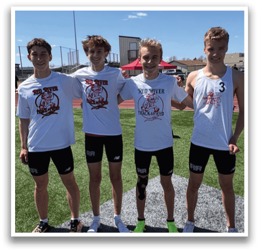 Four young men standing on a field. Description generated by AI