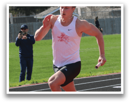 A man running on a track with a red shirt. Description generated by AI