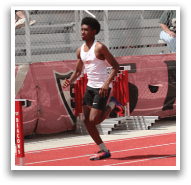 A man running on a track with a red shirt. Description generated by AI
