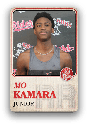 Person wearing a sleeveless athletic shirt and a necklace is posed in front of a backdrop with the text “RRHS Riders" and a logo, with the name "Mo Kamara" and "Junior" displayed below. Description generated by AI