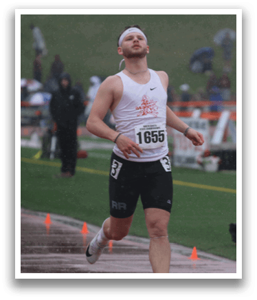 A man running on a track in front of a crowd. Description generated by AI