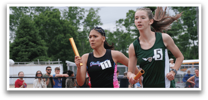 Three girls running on a track, wearing shorts and sprinting towards the finish line. Contenido generado con IA