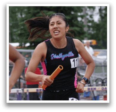 Three girls are running on a track, one wearing a green shirt, another wearing a black shirt, and the third wearing a white shirt. They are all running in the same direction. Contenido generado con IA