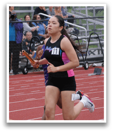 A woman is jumping in the air on a track, wearing a black and white outfit. Contenido generado con IA