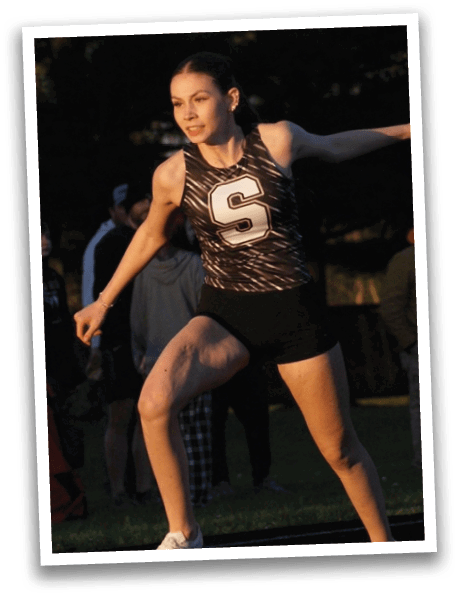 A woman wearing a black and white track suit is running on a track. Contenido generado con IA