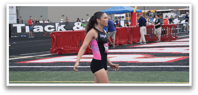 Two female athletes are running on a track, one of them jumping over a hurdle. Contenido generado con IA