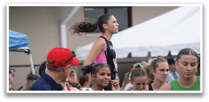 A group of female athletes wearing uniforms and standing on a track. Contenido generado con IA