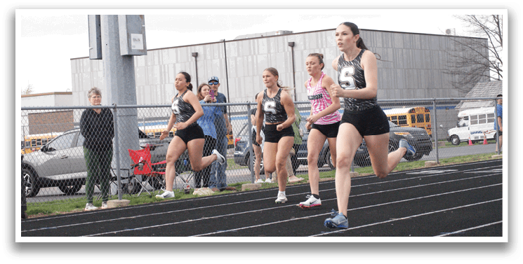 A group of girls are running on a track, with one girl leading the pack. Contenido generado con IA