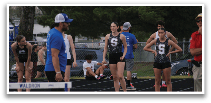 A group of people are standing on a track, some of them wearing blue shirts. Contenido generado con IA