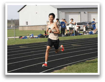 A man is running on a track, wearing a brown shirt and black shorts. He is holding a frisbee in his hand. Contenido generado con IA
