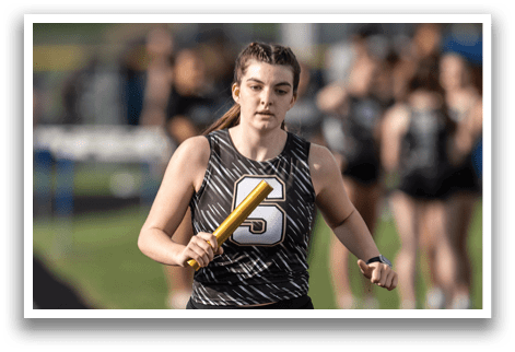 A female athlete is running on a track while holding a yellow bat. Contenido generado con IA