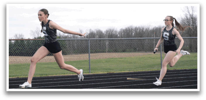 Two female runners are shown on a track, one in the foreground and the other in the background. Both are wearing black and white outfits and running shoes. The background runner is wearing a number 7 on her shirt. Contenido generado con IA