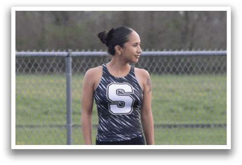 A woman wearing a black and white shirt stands on a track. Contenido generado con IA