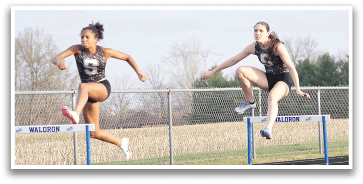 Two women are jumping over hurdles in a track meet. Contenido generado con IA