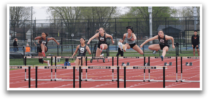 Three female athletes are jumping over hurdles in a track competition. Contenido generado con IA
