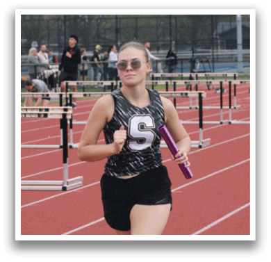 A female athlete wearing a black and white uniform is running on a track. Contenido generado con IA