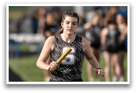 A female athlete is running on a track while holding a yellow bat. Contenido generado con IA