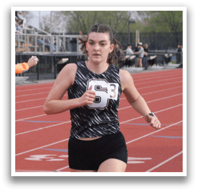 A woman is running on a track while wearing a black and white shirt. Contenido generado con IA